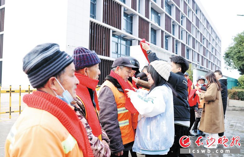 1月3日,来自湖南工艺美术职业学院的大学生给环卫工人戴上亲手编织的围巾。 长沙晚报通讯员 盛磊 全媒体记者 石祯专 摄影报道